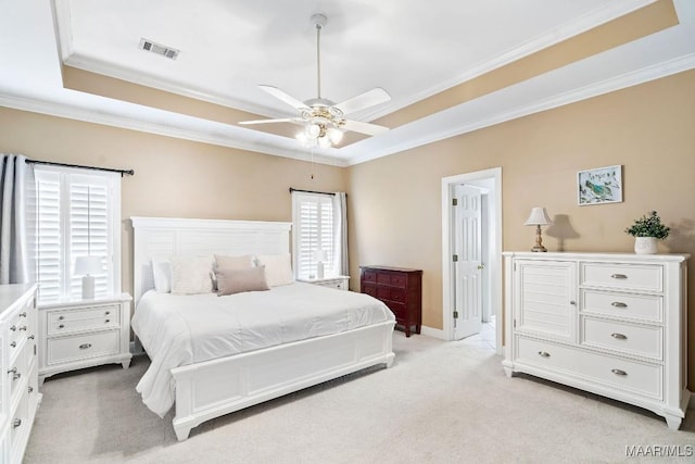 carpeted bedroom featuring ceiling fan, a raised ceiling, and ornamental molding