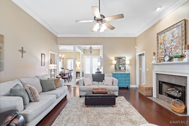 living room featuring dark hardwood / wood-style floors, crown molding, ceiling fan with notable chandelier, and a tile fireplace