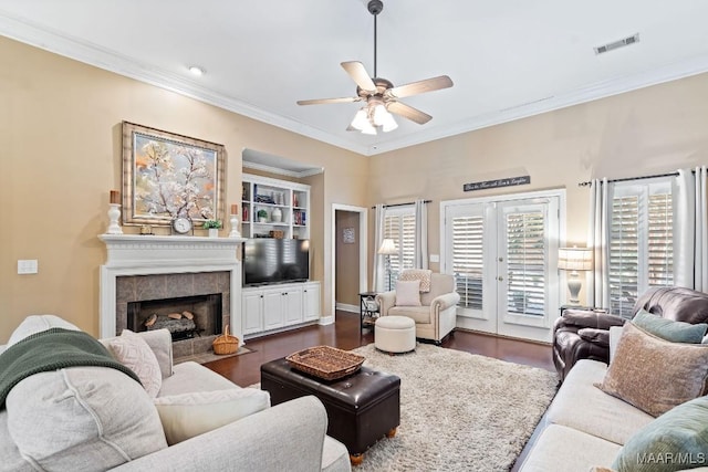 living room featuring a tile fireplace, ceiling fan, french doors, dark hardwood / wood-style floors, and ornamental molding