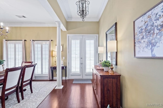 entryway featuring ornate columns, a healthy amount of sunlight, dark wood-type flooring, and a chandelier