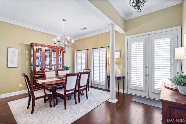 dining area with a healthy amount of sunlight, dark hardwood / wood-style flooring, decorative columns, and a notable chandelier