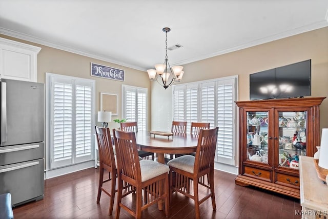 dining area featuring dark hardwood / wood-style flooring, crown molding, and a chandelier