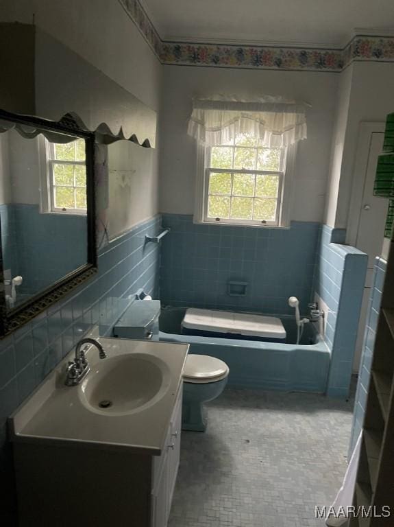 bathroom with vanity, toilet, tile walls, and a healthy amount of sunlight