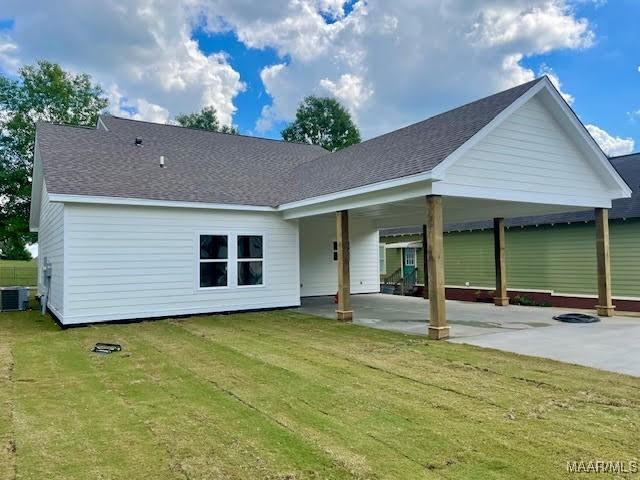 rear view of house with a yard, central AC unit, and a carport