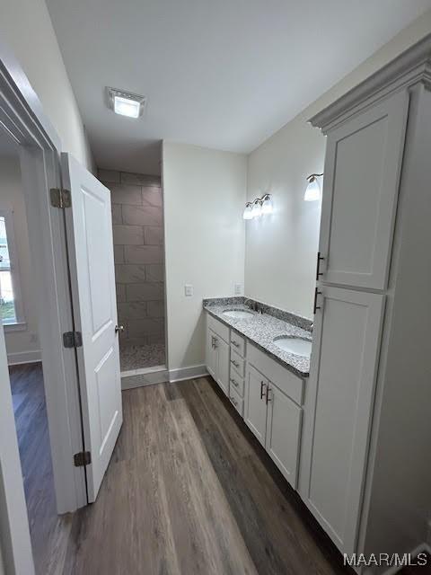 bathroom with hardwood / wood-style flooring, vanity, and tiled shower