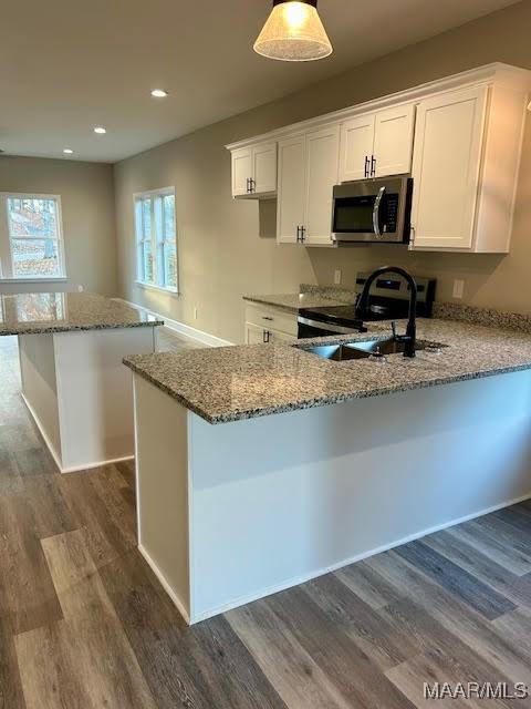 kitchen featuring white cabinetry, dark hardwood / wood-style flooring, electric range, and decorative light fixtures