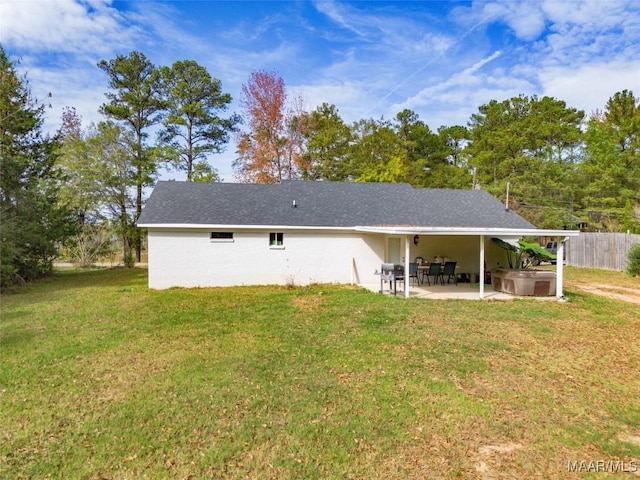 rear view of house with a lawn, a patio, and a hot tub