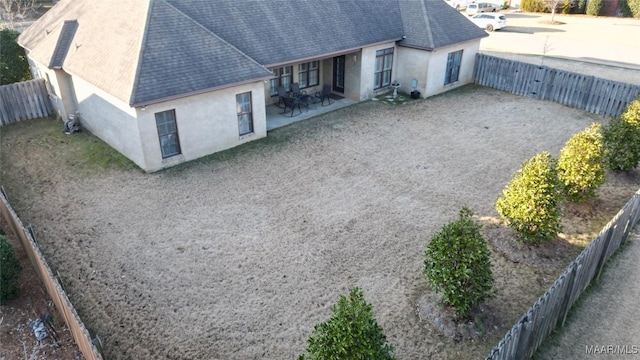 8513 Rockbridge Cir, Montgomery, AL 36116 - rear view of house with stucco siding, roof with shingles, a patio, and a fenced backyard