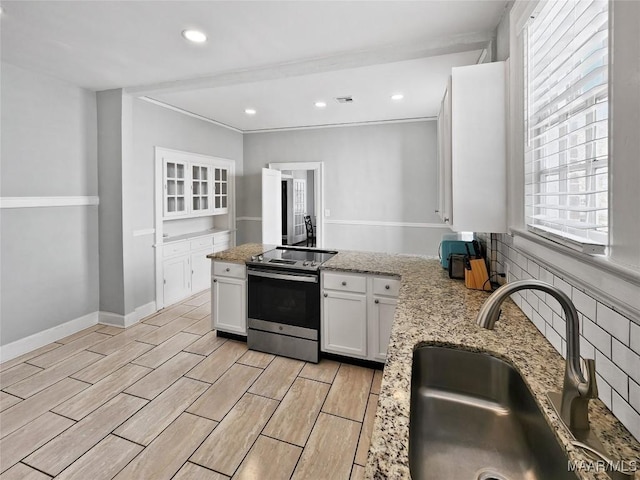 kitchen with white cabinets, sink, light stone counters, and stainless steel electric range