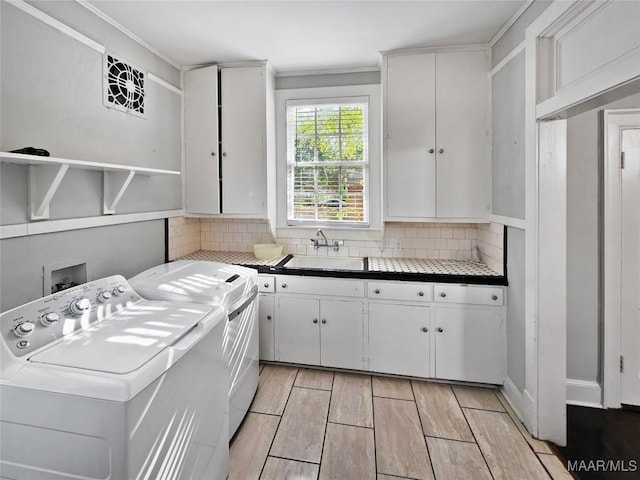 laundry area with washer and dryer, ornamental molding, cabinets, and sink