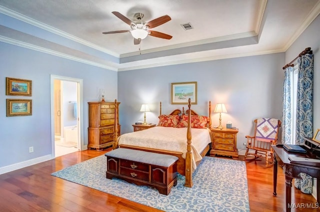 bedroom with ensuite bath, a tray ceiling, ceiling fan, crown molding, and wood-type flooring