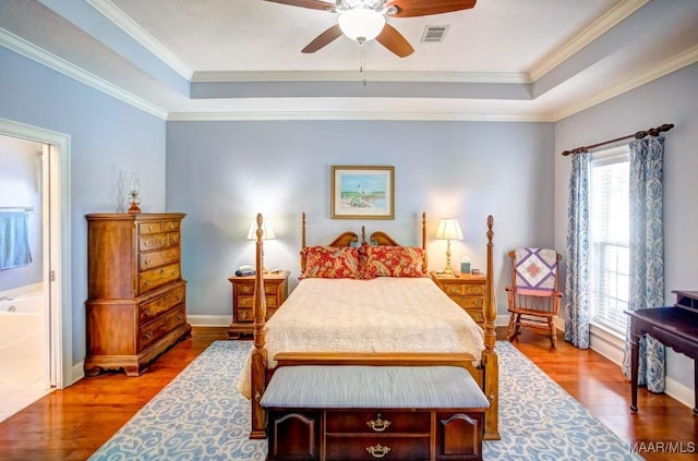 bedroom with hardwood / wood-style floors, a tray ceiling, ceiling fan, and ornamental molding