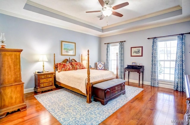 bedroom featuring light wood-type flooring, a tray ceiling, ceiling fan, and ornamental molding