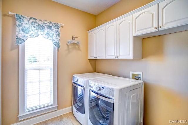 laundry area with washer and dryer, cabinets, and light wood-type flooring