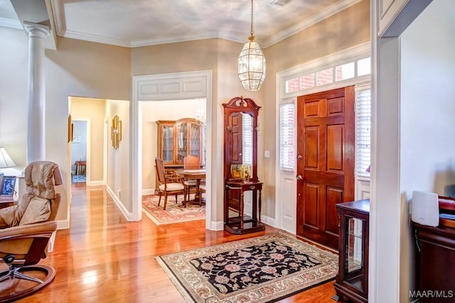 foyer with decorative columns, crown molding, light hardwood / wood-style floors, and a notable chandelier