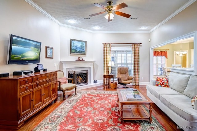 living room featuring wood-type flooring, ceiling fan with notable chandelier, a textured ceiling, and ornamental molding