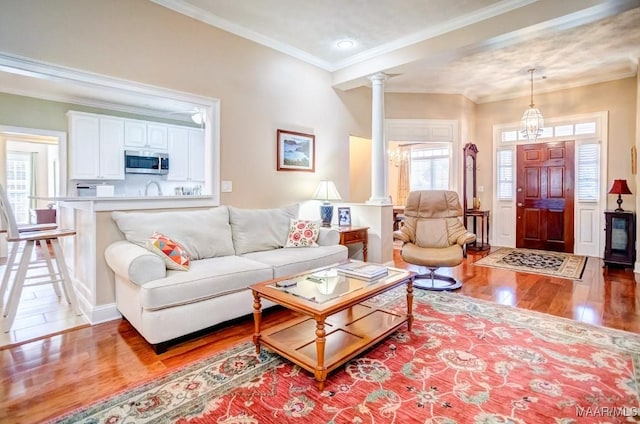 living room featuring light hardwood / wood-style floors, ornate columns, plenty of natural light, and ornamental molding