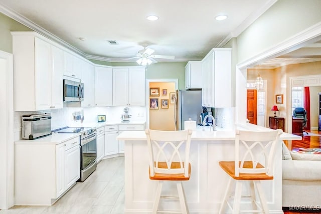 kitchen with white cabinetry, stainless steel appliances, kitchen peninsula, pendant lighting, and a breakfast bar area