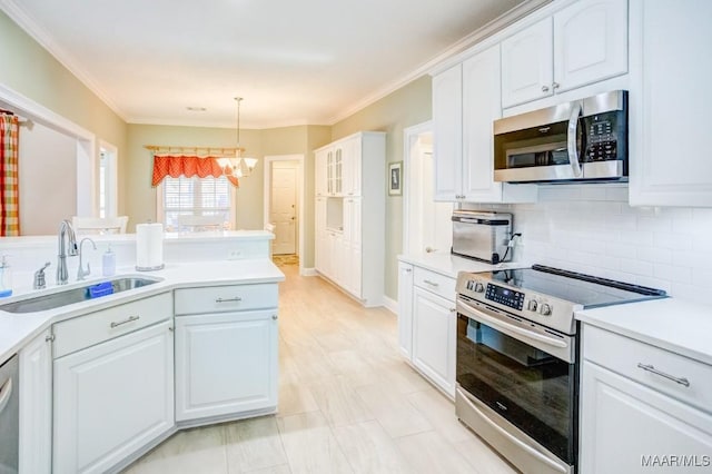 kitchen featuring an inviting chandelier, hanging light fixtures, sink, appliances with stainless steel finishes, and white cabinetry