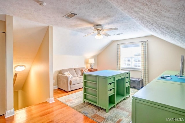 bedroom featuring a textured ceiling, ceiling fan, light hardwood / wood-style floors, and vaulted ceiling