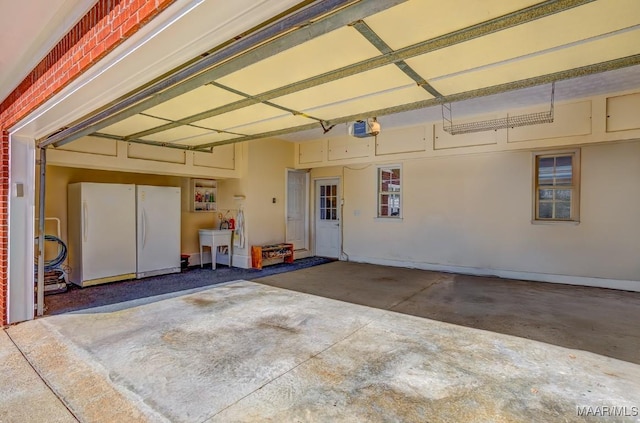 garage featuring sink, white fridge, and a garage door opener