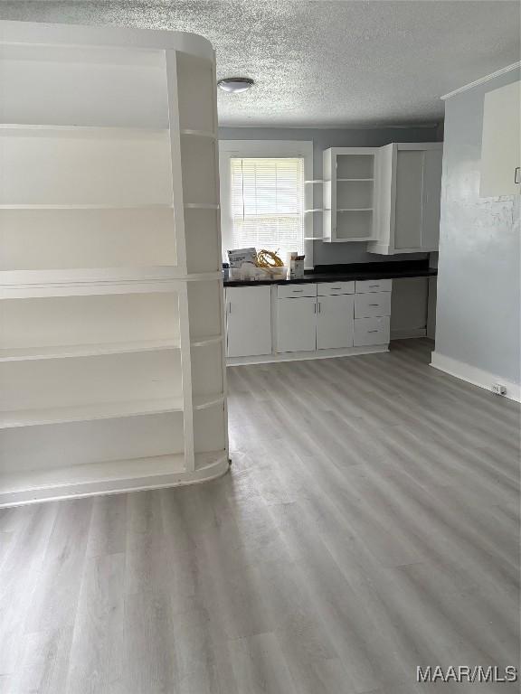 kitchen featuring hardwood / wood-style floors, white cabinetry, and a textured ceiling