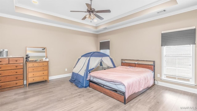 bedroom with light hardwood / wood-style flooring, a raised ceiling, ceiling fan, and ornamental molding