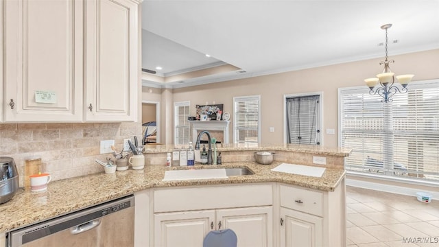 kitchen with sink, stainless steel dishwasher, a tray ceiling, a notable chandelier, and kitchen peninsula