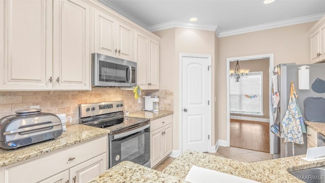 kitchen featuring stainless steel appliances, an inviting chandelier, crown molding, decorative backsplash, and light tile patterned floors