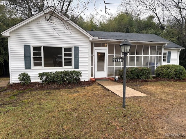 view of front facade with a front lawn and a sunroom