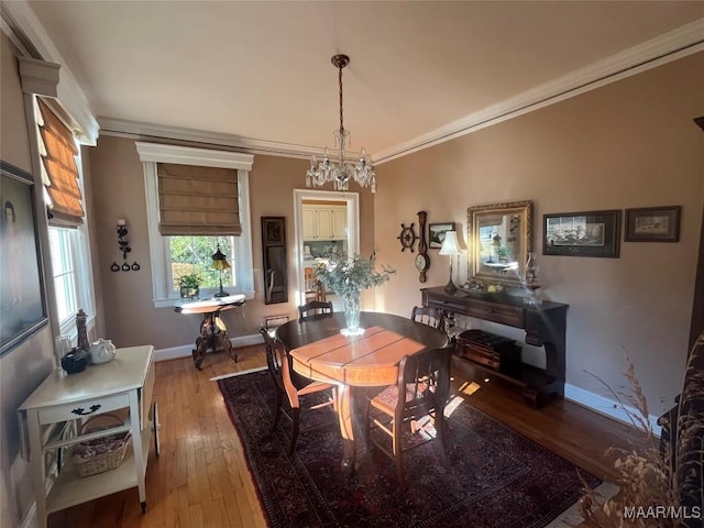 dining space with crown molding, a chandelier, and light wood-type flooring