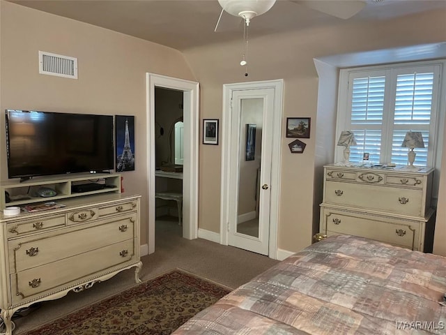 bedroom featuring dark colored carpet, ensuite bath, ceiling fan, and lofted ceiling