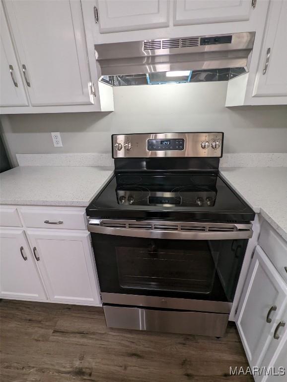 kitchen featuring stainless steel electric range oven, dark hardwood / wood-style flooring, white cabinets, and exhaust hood