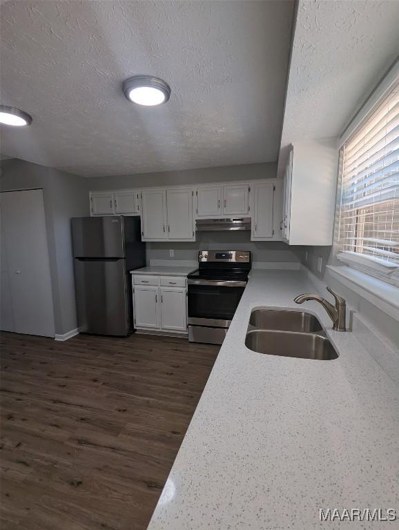 kitchen featuring dark hardwood / wood-style flooring, a textured ceiling, stainless steel appliances, sink, and white cabinetry