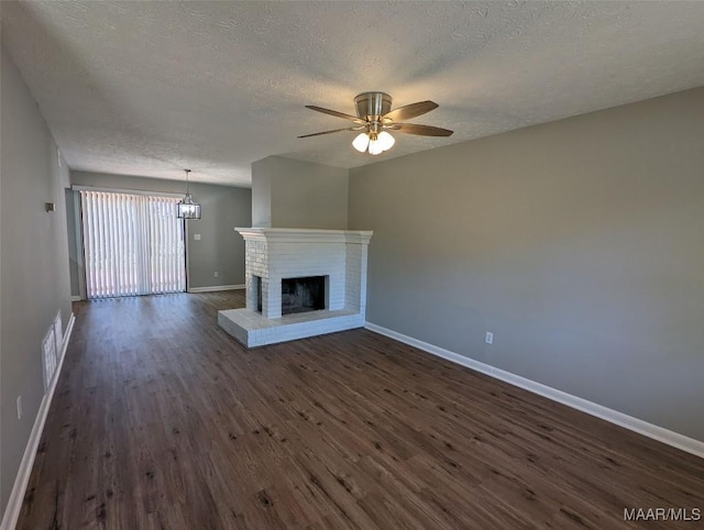 unfurnished living room featuring dark hardwood / wood-style floors, ceiling fan, a textured ceiling, and a brick fireplace