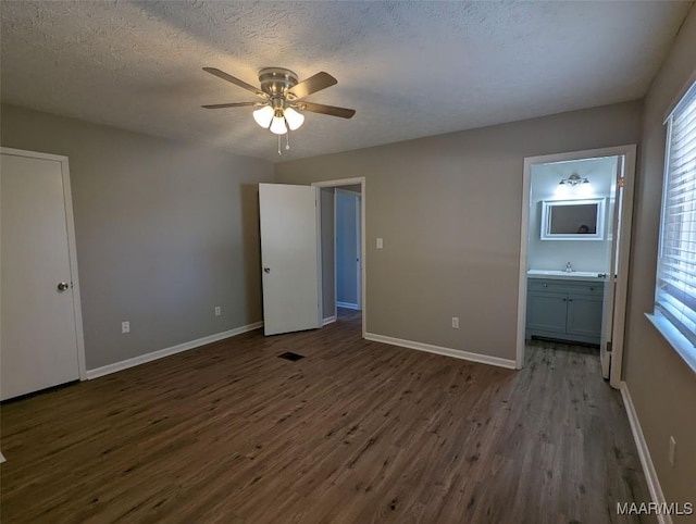 unfurnished bedroom featuring dark hardwood / wood-style flooring, ensuite bath, a textured ceiling, ceiling fan, and sink