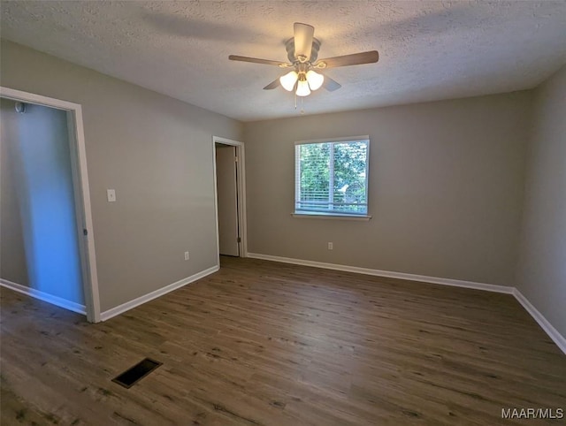 empty room featuring a textured ceiling, ceiling fan, and dark wood-type flooring