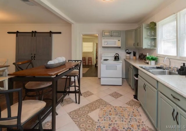 kitchen with sink, tasteful backsplash, a barn door, crown molding, and white appliances