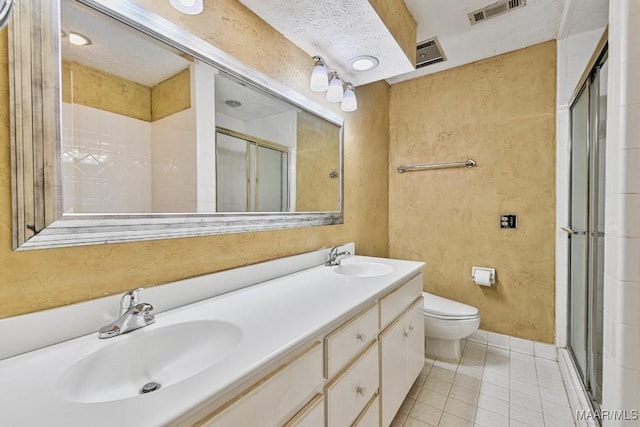 bathroom with tile patterned floors, walk in shower, vanity, a textured ceiling, and toilet