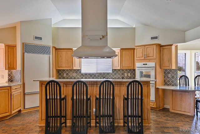 kitchen with decorative backsplash, island range hood, a center island, built in refrigerator, and lofted ceiling