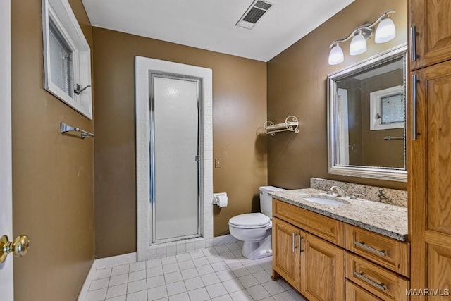 bathroom featuring toilet, vanity, tile patterned floors, and a shower with shower door