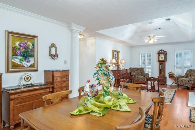 dining area featuring hardwood / wood-style flooring, ceiling fan, ornate columns, and ornamental molding