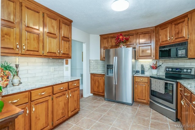 kitchen with backsplash, light stone countertops, a textured ceiling, light tile patterned floors, and stainless steel appliances