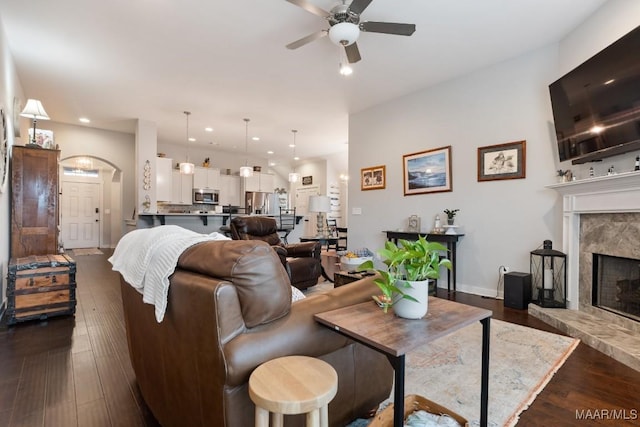 living room featuring ceiling fan, dark hardwood / wood-style flooring, and a premium fireplace