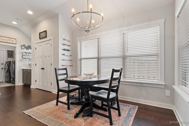 dining room featuring a chandelier, washing machine and dryer, vaulted ceiling, and dark wood-type flooring