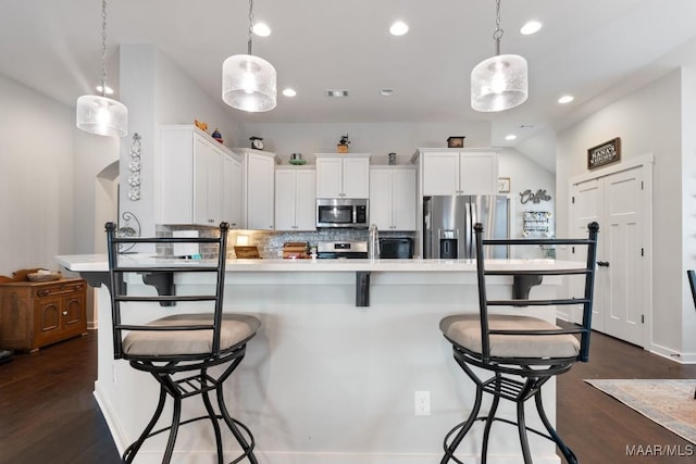 kitchen with a breakfast bar, backsplash, hanging light fixtures, white cabinetry, and stainless steel appliances