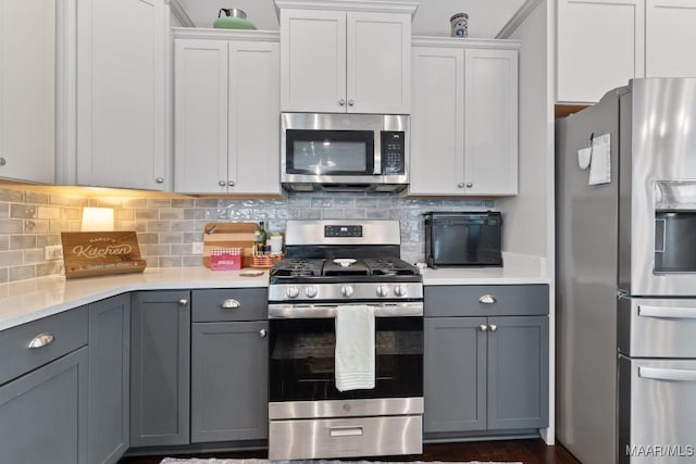 kitchen with backsplash, gray cabinets, white cabinets, and appliances with stainless steel finishes