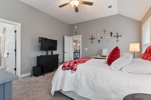 carpeted bedroom with ceiling fan, lofted ceiling, and ensuite bath