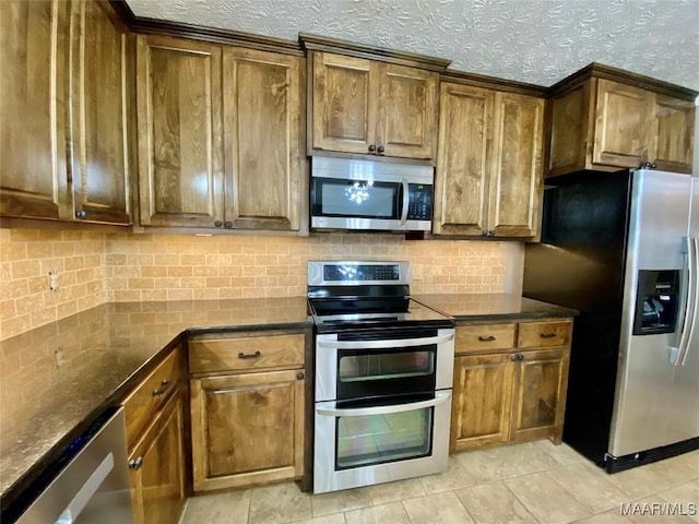 kitchen featuring appliances with stainless steel finishes, a textured ceiling, light tile patterned floors, and dark stone countertops