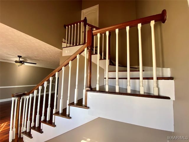 stairs with ceiling fan and a textured ceiling